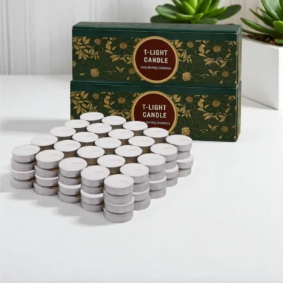 Stacked white wax tealight candles in silver aluminum cups in front of a yellow floral T-Light Candle box