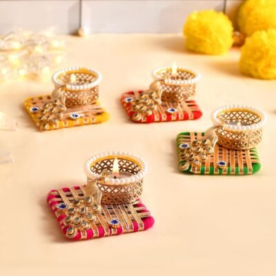 Four handcrafted peacock thread tealight holders in yellow, red, pink, and green with pearl-rimmed golden cups and lit candles