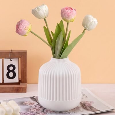 White Plastic Flower Pot with vertical ribbed fluting resting on a wooden tabletop.