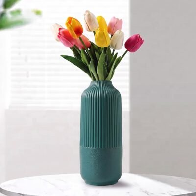 Green Plastic Flower Pot with vertical ribbed fluting on top and a textured base resting on a white table.