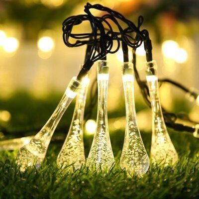 Warm white waterdrop fairy string lights glowing on green grass