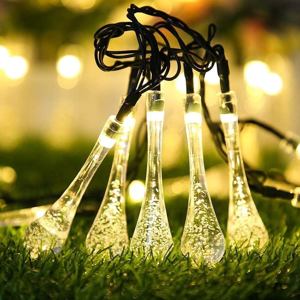 Warm white waterdrop fairy string lights glowing on green grass