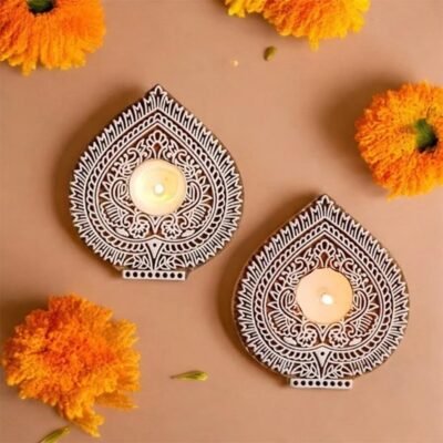Hand carved wooden paan leaf tealight holders with white painted patterns and lit candles