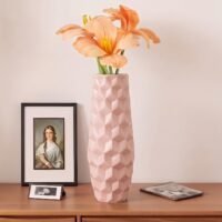 Modern pastel pink plastic flower pot with a textured geometric pattern on a white tabletop