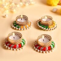 Handcrafted pearl and thread work tealight candle holders with lit candles on a cream background