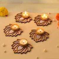 Wooden laser-cut lotus shape tealight candle holders with gold metal cups and lit candles on a cream background