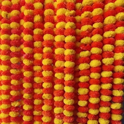 Yellow and orange artificial marigold garland for decoration hanging as a lush festive floral backdrop.