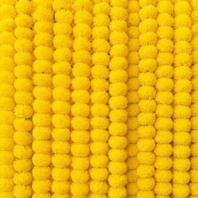 Add traditional warmth to your celebrations with 10 Pcs Yellow Handmade Artificial Marigold Flowers. Skilled artisans handcraft each string in this ten-piece set with full blossoms. They quickly brighten up any room or entrance. You can create a full mandir backdrop for Diwali. You can decorate entrance doors for housewarming functions. You can also craft a photo background for wedding ceremonies. These yellow marigold garlands add instant traditional style. Fresh flowers dry out quickly. In contrast, these artificial garlands retain their fluffiness and vivid color. They are light in weight. You can easily hang them along walls, railings, doorways, and arches. Pack them away safely after your function. This ten-piece set offers a practical, reusable solution for your festive decoration.