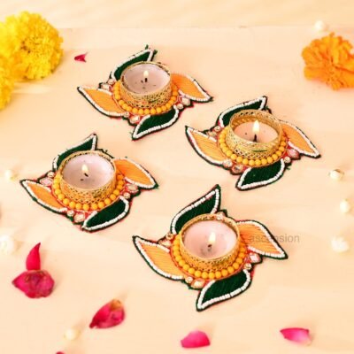 Handcrafted swastik shaped tealight candle holders with green and yellow thread work and lit candles on a light surface