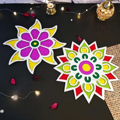 Two wooden floral rangoli mats in vibrant purple, yellow, red, and green on a dark surface
