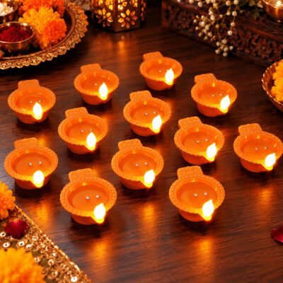 Pack of 12 water sensor diya units emitting warm ambient light on a wooden table.