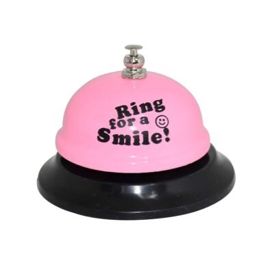 Pink desk call bell featuring the text Ring for a Smile with a smiley face on a black base