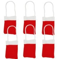 Six mini red Christmas treat bags with white cuffs and string handles hanging against a white background.