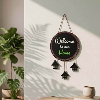 Circular black Welcome Home Wall Hanging with decorative house cutouts hanging below on a light wall.