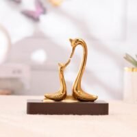 Glossy golden swan pair figurine facing each other on a dark rectangular base