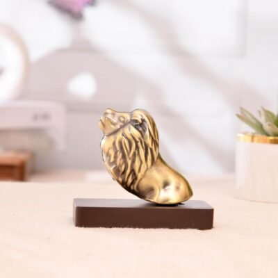 Antique brass lion head figurine mounted on a rectangular dark wooden base