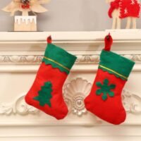 Two red and green felt Christmas stockings hanging on a white mantelpiece, featuring tree and snowflake designs.
