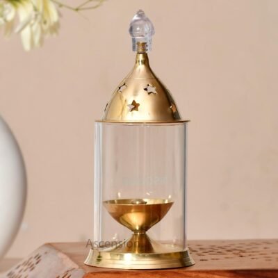 Brass Akhand Jyot diya with clear glass cover and star cutout brass lid on wooden surface