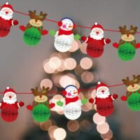 Two rows of a Christmas honeycomb garland featuring Santa, reindeer, and snowmen against a bokeh tree background.