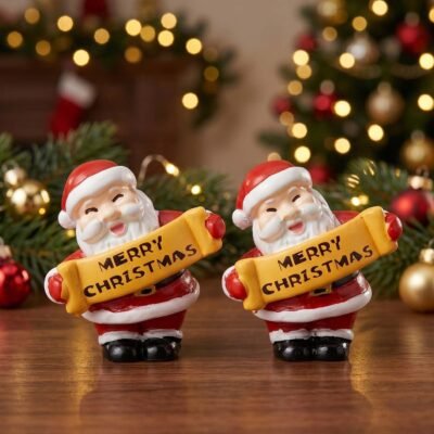 Two miniature Santa Claus figurines holding yellow Merry Christmas banners standing on a wooden table.