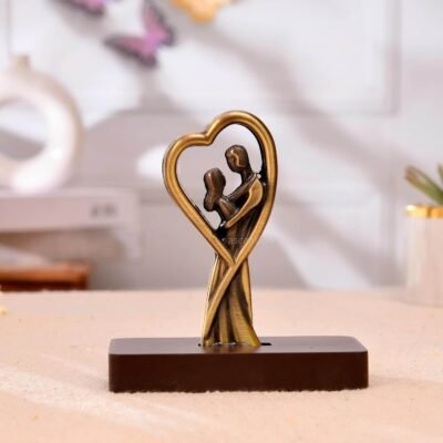 Antique brass figurine of a romantic couple embracing inside a heart frame on a dark base