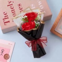 Ascension red rose flower bouquet with two artificial red roses wrapped in gold bordered black paper and a burgundy bow.