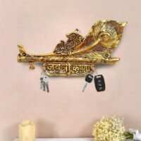 Golden brass Krishna key holder with flute peacock feather design and Jai Shri Krishna inscription mounted on a wall