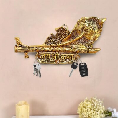 Golden brass Krishna key holder with flute peacock feather design and Jai Shri Krishna inscription mounted on a wall