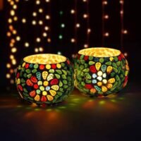 Mosaic Glass Tealight Holder set of two glowing brightly with colorful leaf and floral mosaic patterns on a dark surface.