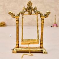 Golden brass Laddu Gopal jhula swing with peacock carvings and pull chain on a light table