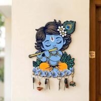 Little Krishna Key Holder wall mount featuring a blue Bal Krishna playing a golden flute with multiple keys hanging from hooks on a beige wall.