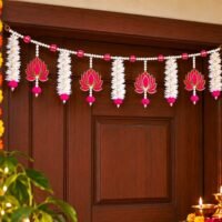 Ascension Lotus Floral Door Toran hanging on a dark wooden door frame featuring white artificial jasmine flowers and pink lotus cutouts.
