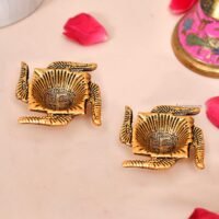Pair of golden brass Swastik shaped diyas with engraved Swastik symbols inside oil cups on a light surface