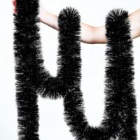 A person's arm holding and draping a long, thick green tinsel garland against a solid white background.