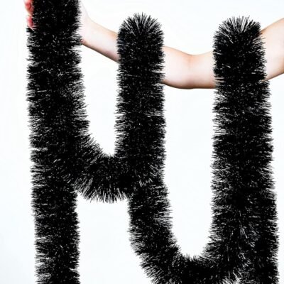 A person's arm holding and draping a long, thick green tinsel garland against a solid white background.