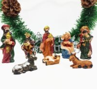 A miniature Nativity scene set featuring the Holy Family, three Wise Men, and animals arranged in front of a green pine garland.