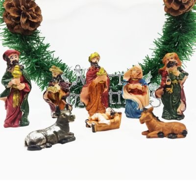 A miniature Nativity scene set featuring the Holy Family, three Wise Men, and animals arranged in front of a green pine garland.