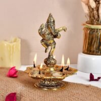 Brass dancing Ganesha aarti diya with five lit cotton wicks on jute mat