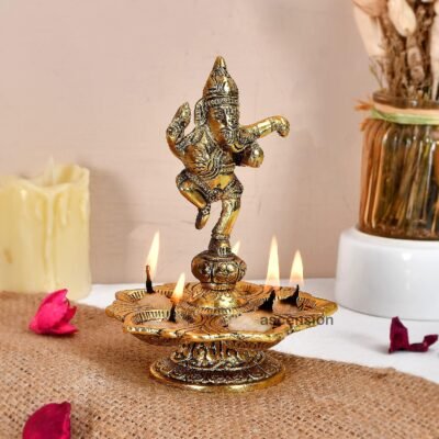 Brass dancing Ganesha aarti diya with five lit cotton wicks on jute mat