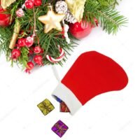 Two plain red Christmas stockings with white cuffs hanging below a decorated pine garland against a white wooden wall.
