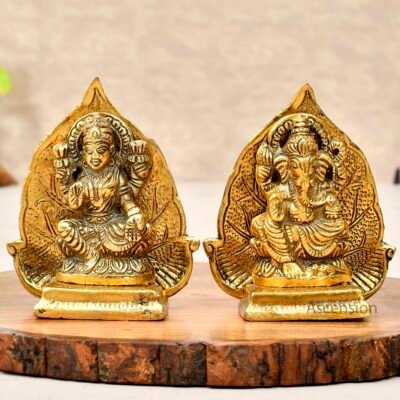 Golden brass Goddess Lakshmi and Lord Ganesha idol set with peepal leaf backdrop on wooden slab