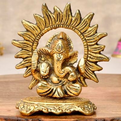 Golden brass Sun Ganesha idol with radiant sun ray halo on a wooden surface