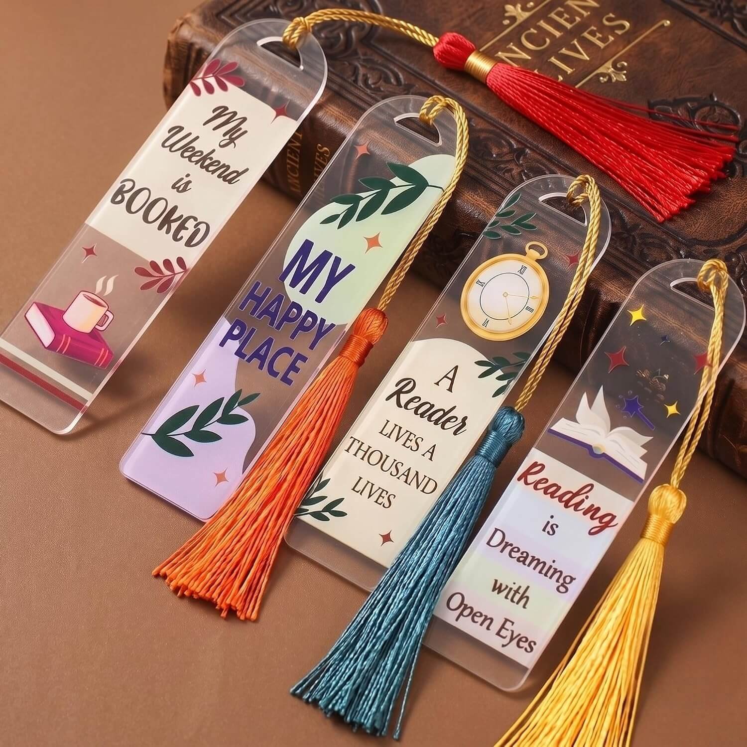 Acrylic Bookmark Tassel Set displaying clear bookmarks with inspirational reading quotes and colorful silk tassels resting on a book.
