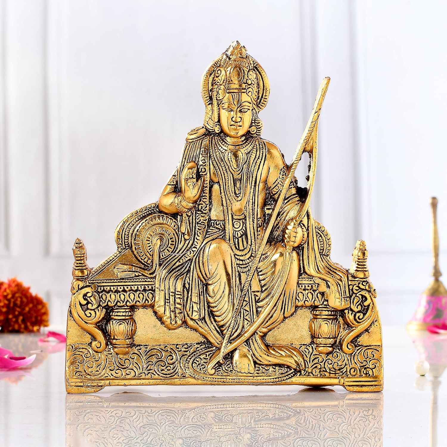 Golden brass Ram Lalla idol holding a bow and seated on a royal throne on a white surface