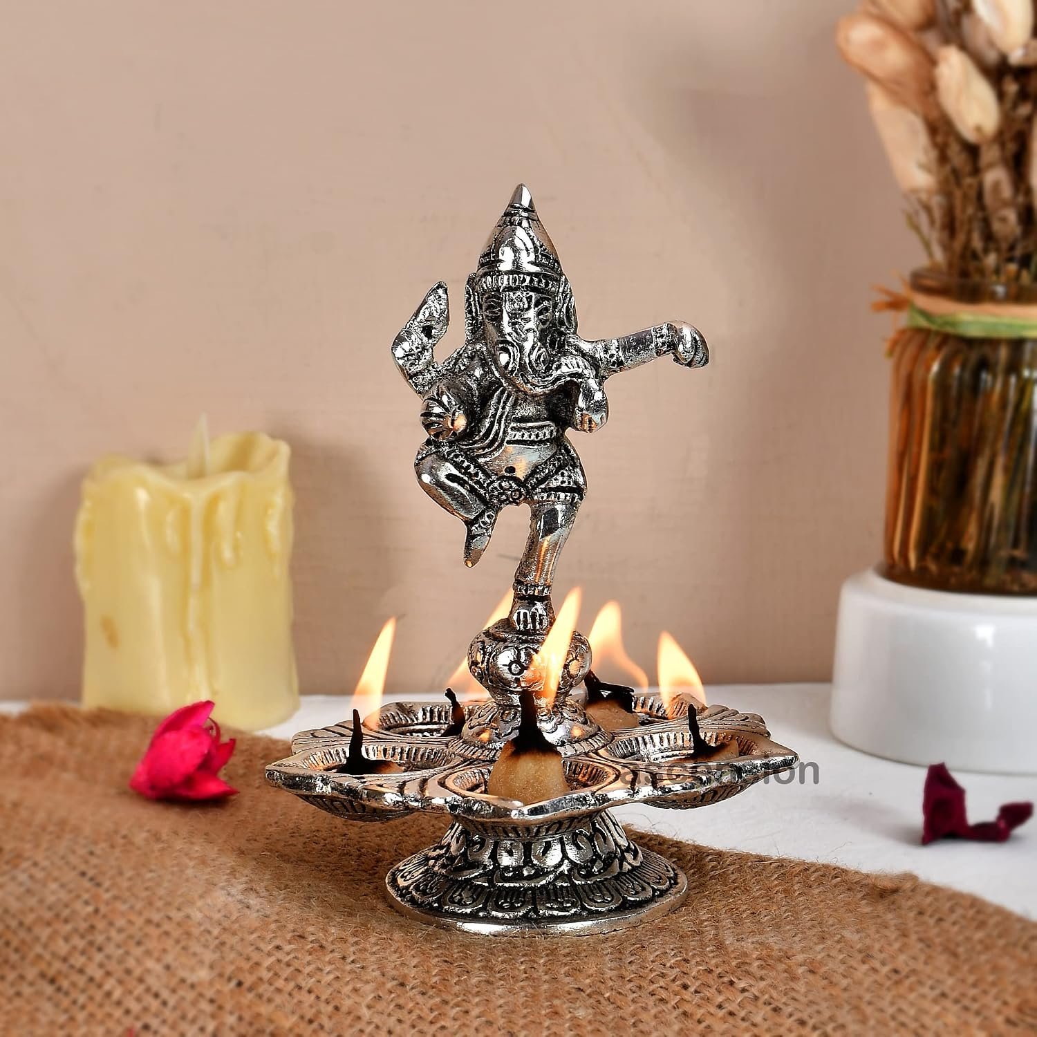 Antique silver dancing Ganesha aarti diya with five lit cotton wicks on jute runner
