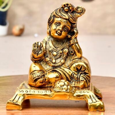 Golden brass Laddu Gopal idol sitting on a chowki platform resting head on hand