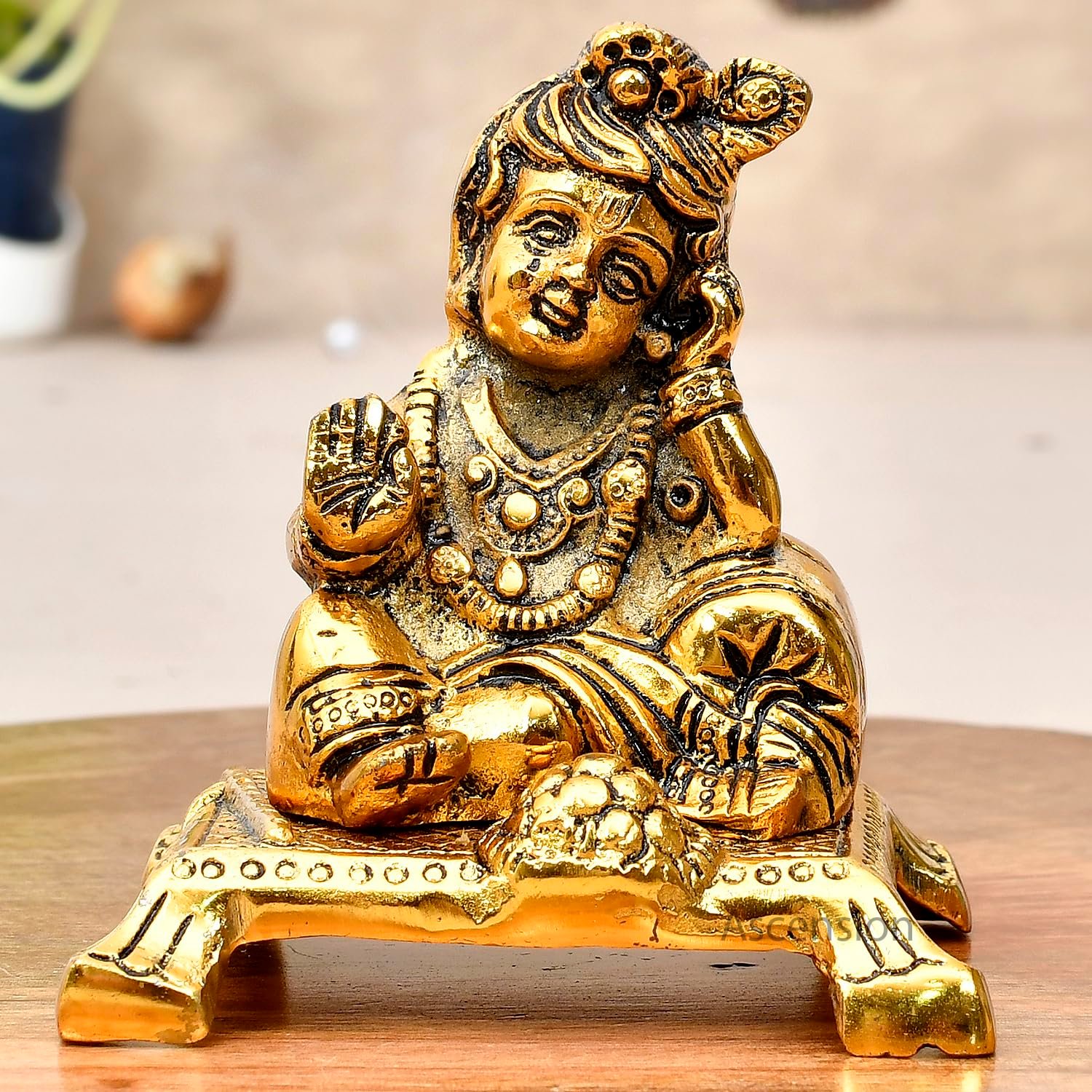 Golden brass Laddu Gopal idol sitting on a chowki platform resting head on hand