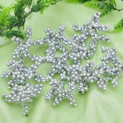 Several metallic silver berry picks featuring clusters of round beads arranged on a light green fabric background.