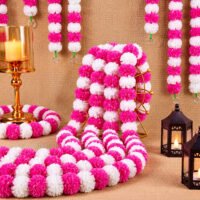 Pink Artificial Marigold Garlands pack of 5 displayed with pink and white artificial pom-pom flowers alongside lanterns and candle holders on a burlap backdrop.