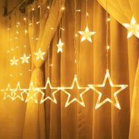 Warm white star curtain string lights hanging in vertical strands with glowing star ornaments